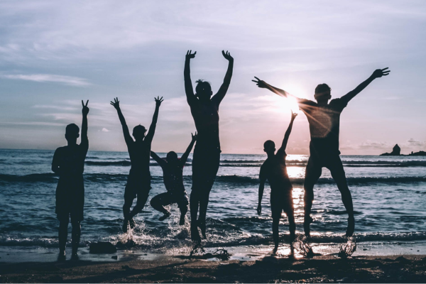 Family on the beach jumping in victory after they have been healed.
